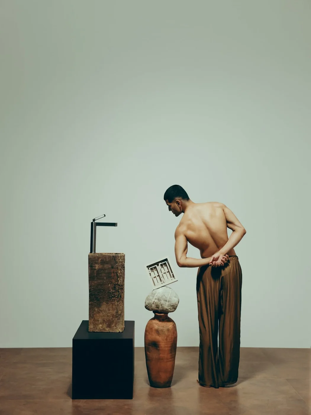 Model beside stone plinths with an Elbe tall faucet and terracotta vessels